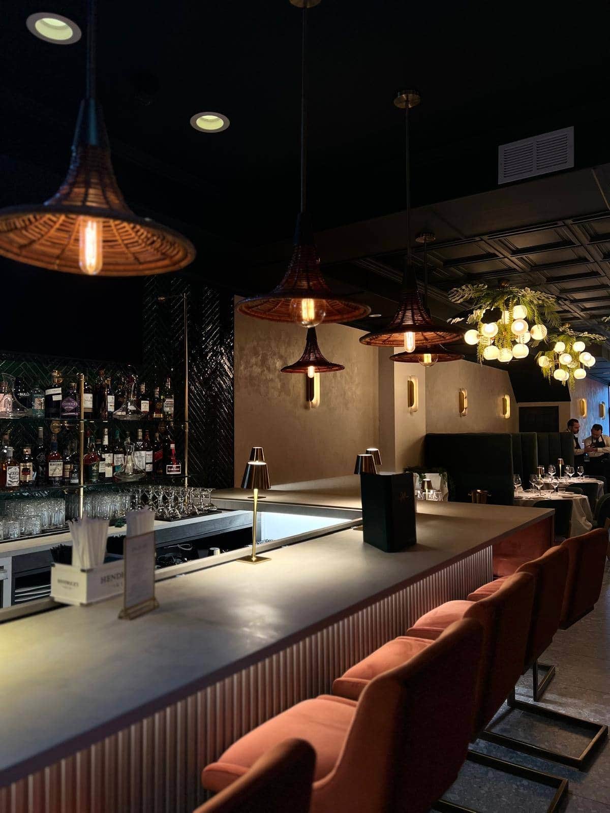 The bar at Casa Stellina in Farmingdale, NY, at service — rattan pendants and green velvet