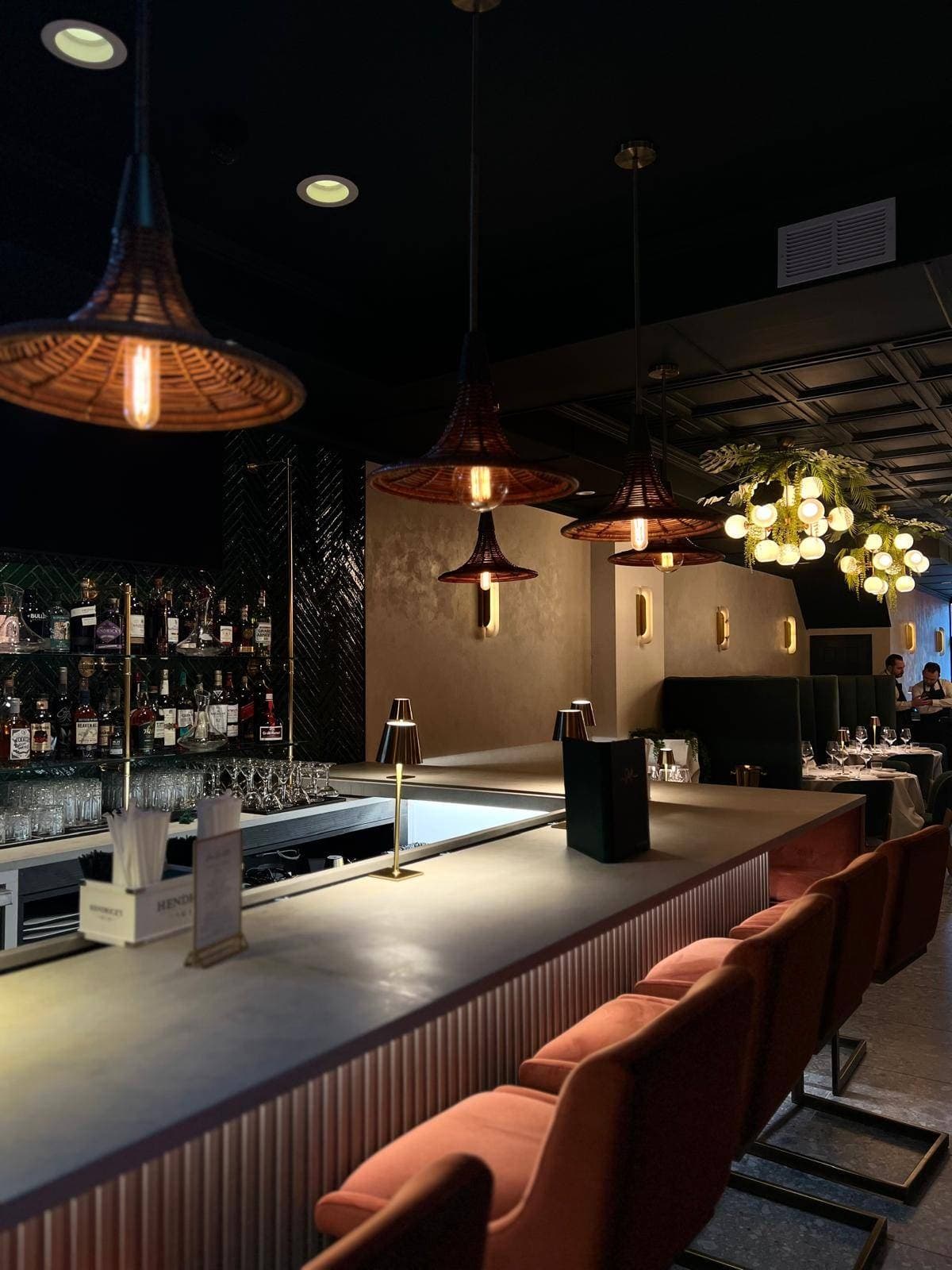 The bar at Casa Stellina in Farmingdale, NY, at service — rattan pendants and green velvet